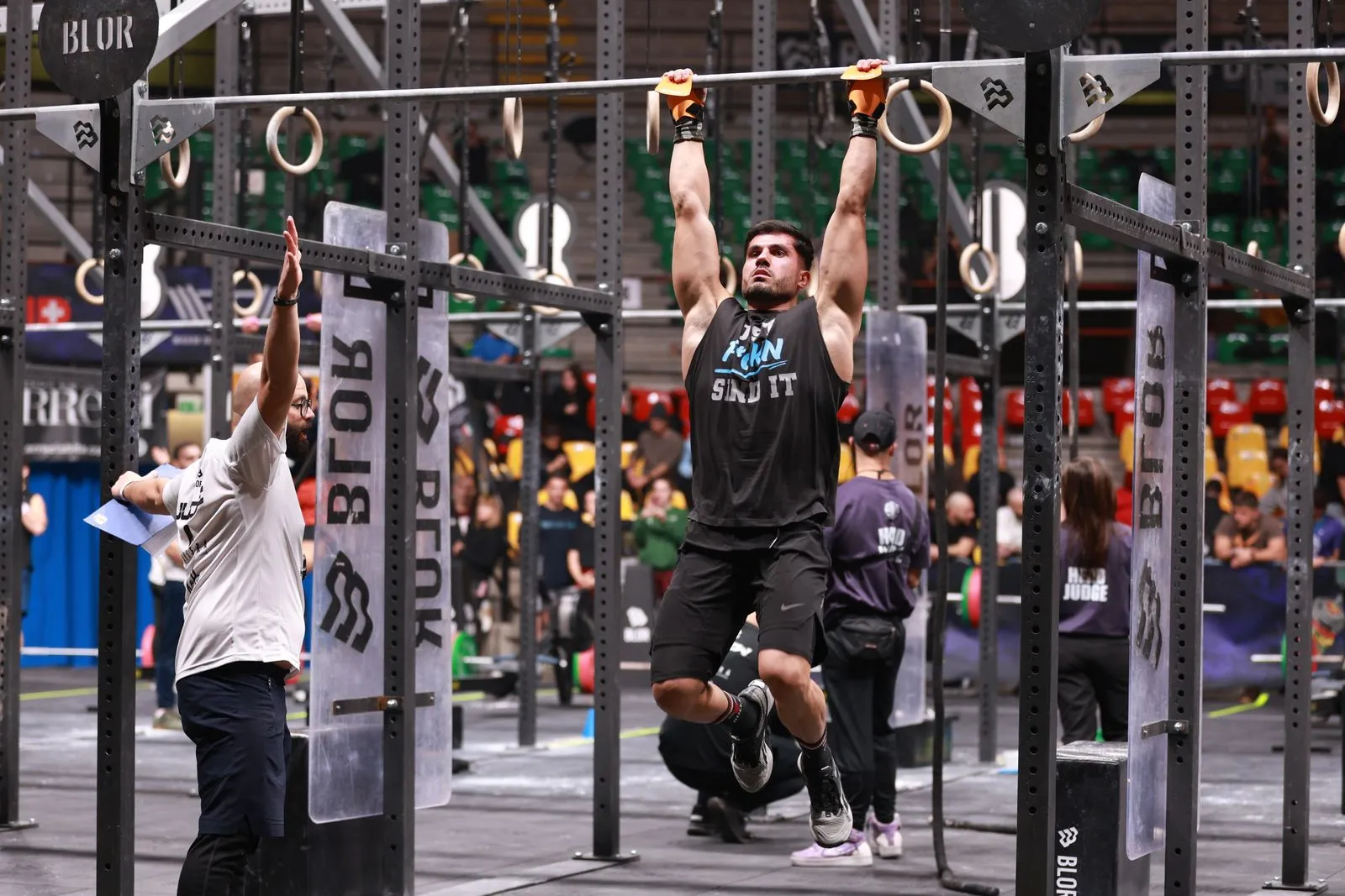 Athlete performing pull-ups during a competitive CrossFit event indoors.